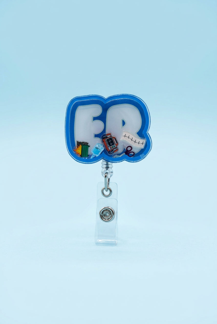 ER shaker badge reel with light blue lettering, a blue border, and miniature cardiac monitor, ECG strip, IV bag, trauma shears, and dumpster fire.