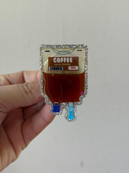 Hand holding a novelty coffee bag shaped like a medical IV bag on a plain background