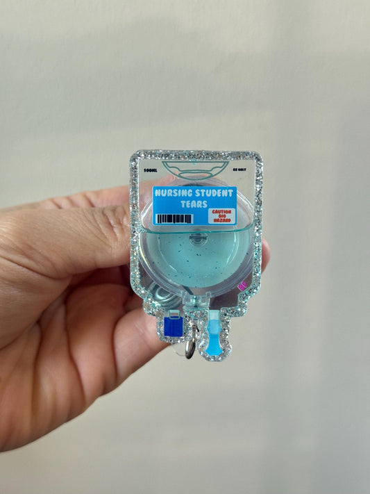 Hand holding a small blue container labeled 'Nursing Student Tears' against a plain background